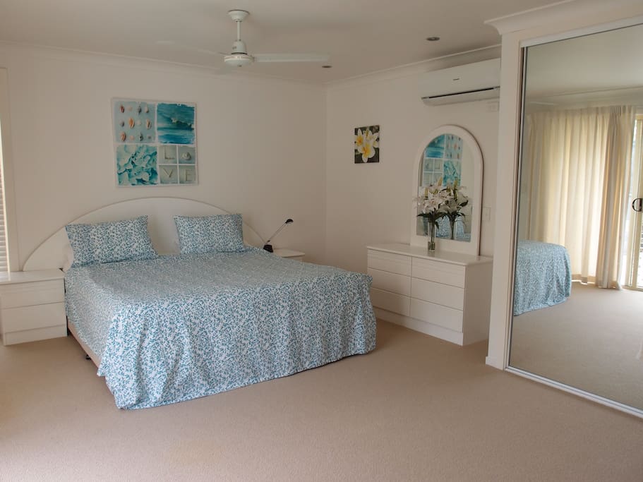 King sized bed with ensuite and view of pool, with flat screen TV on wall.