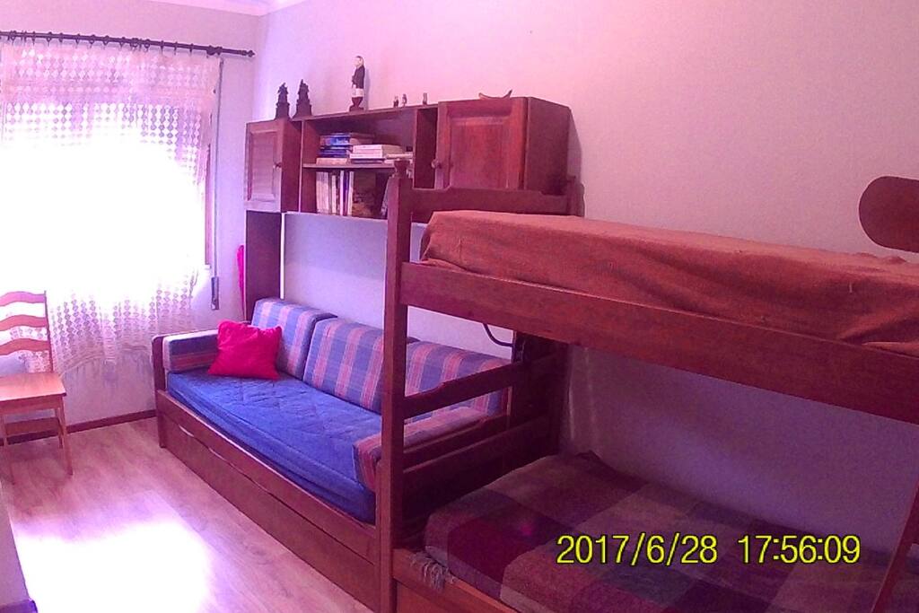 Quarto de solteiros. Além dos 2 beliches, o sofá é uma terceira cama, tendo ainda uma cama-gaveta por baixo.
Singles room. In addition to the bunk beds, the sofa is a third bed With a fourth bed underneath.