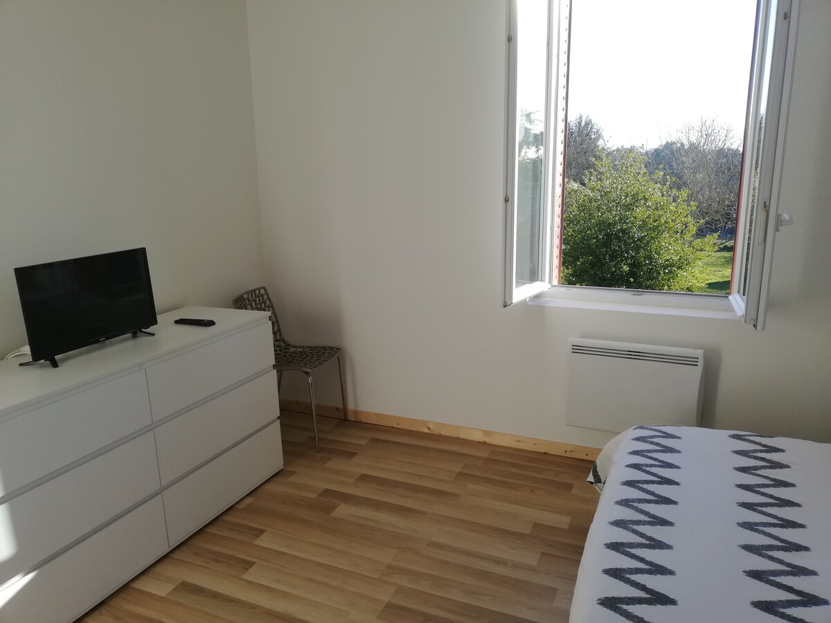 卧室里有一台电视、带羽绒被和枕头的抽屉柜、一台带灯的平板电脑和一把额外的椅子。 
