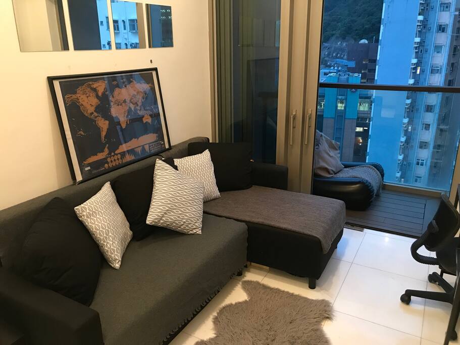 Living room with double fold out sofa, desk and balcony with city and greenery views