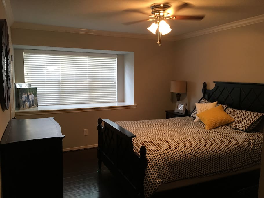 Bedroom 1 with private bathroom and large window overlooking tree lined walkway.