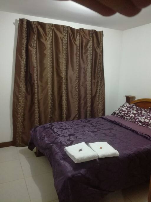 cama matrimonial y cortinas que cubren la luz exterior.