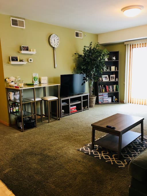 Living room with flat screen TV and pub table with stools.