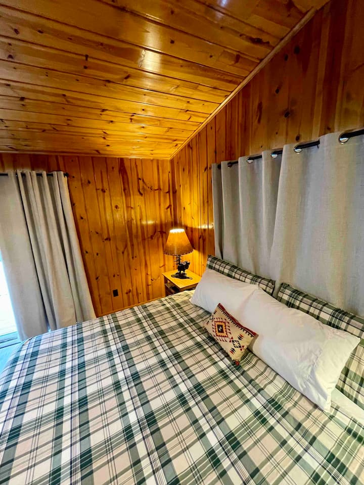 غرفة نوم رئيسية بسرير كينج مع منزلق كامل إلى السطح الكبير المطل على البحيرة. 