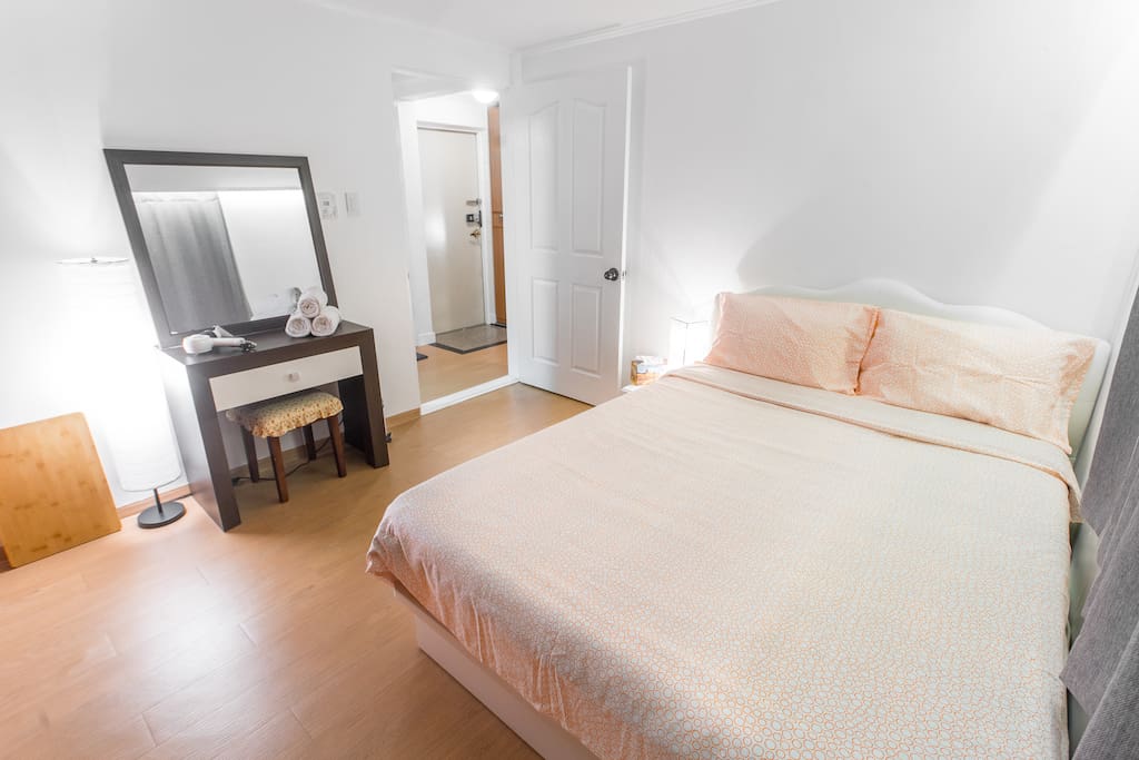 Bedroom #1, with a massive closet, a queen size bed with a latex topper, a nightstand, a bed table, and a mirror and desk.