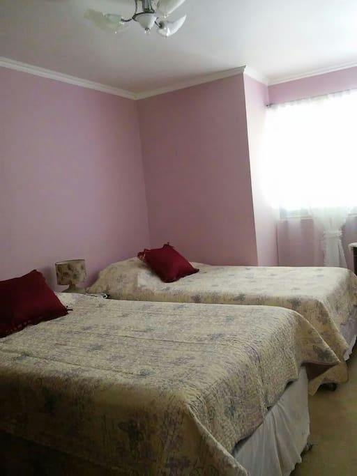 Habitación con dos camas y baño privado dentro de ésta.