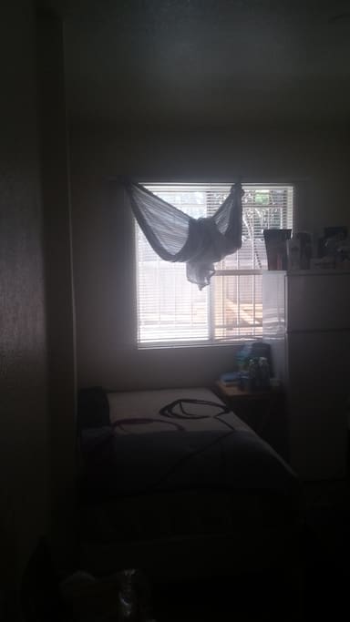 This is the bed next to the window there a little foldable table in the room also .