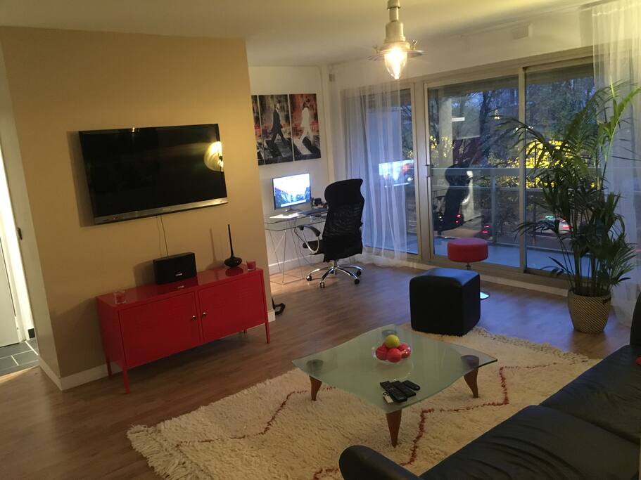 Grand living room avec canapé convertible, en lit deux places, télévision 120 cm, consoles de jeux (PS4, Wii U) et Apple TV et espace de travail et accès à la terrasse.