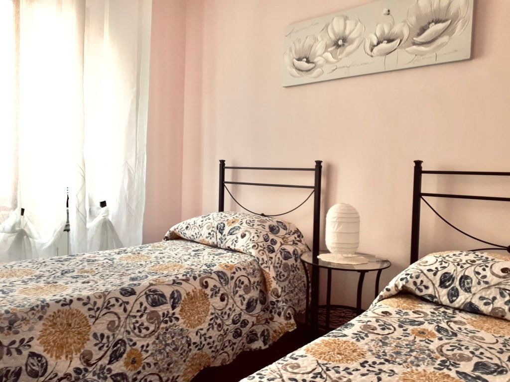 first room consisting of two single beds, with bedding included, wardrobe with 2 doors, bedside table , window overlooking the village