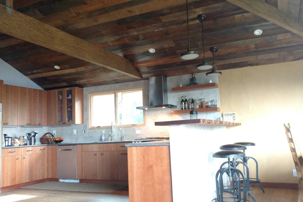 Modern kitchen with bar table, stools , adjacent dining room table that fits for 4-6 people and the living room with the view attached.