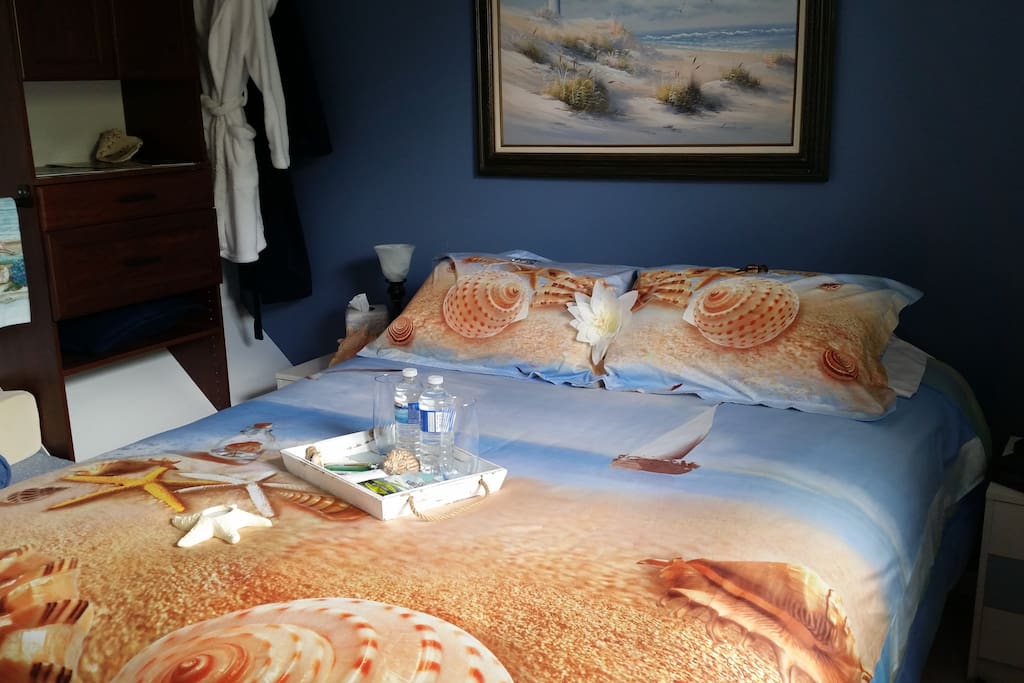 Beach themed Queen bed across from shared bathroom.