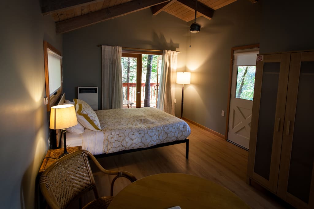 The guest cottage bedroom. French doors lead out to a deck shaded by trees.