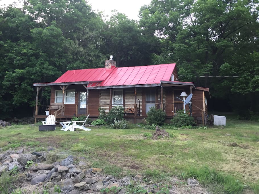 View of cottage from meadow. The outdoors is equipped with a BBQ, fire pit, comfy chairs, garden torches. What more do you need for a romantic hang-out?!