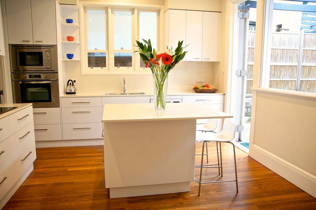 Bright kitchen with centre table and kiosk style bar opening to deck
