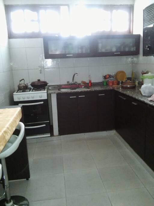 cocina con mesada y cocina con gas natural, calefon y heladera. Un equipo de aire acondicionado en la cocina comedor. Hay un desayunador de 2 mts con 6 banquetas giratorias.