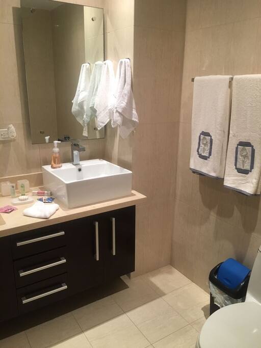 Baño espacioso totalmente equipado con agua caliente, tina de baño, dos lavamanos y ropa de baño como toallas jabones y champú