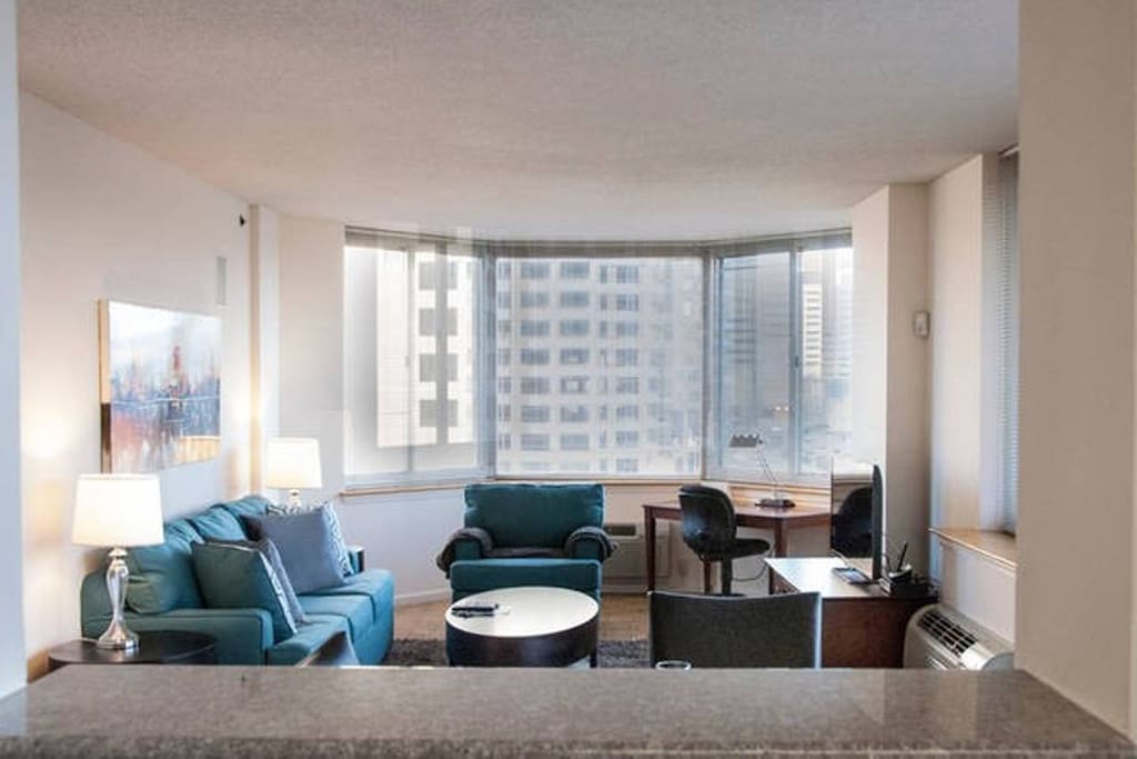 Comfortable living room with pullout sofa bed, club chair and over-sized windows providing a lot of natural light