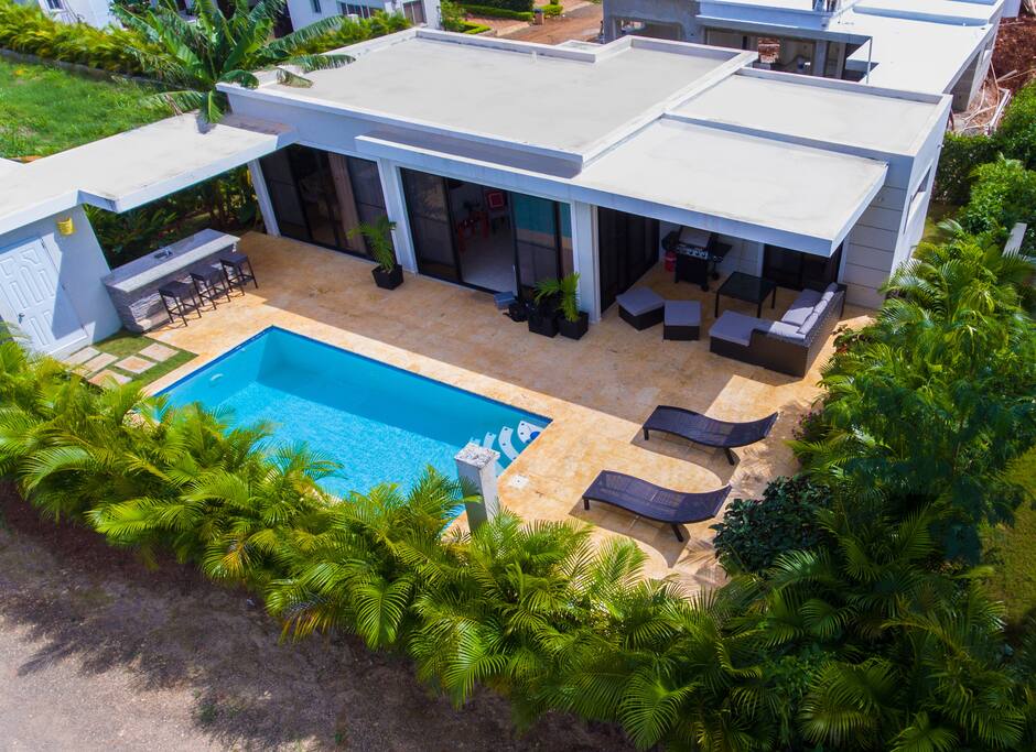 Aerial view of villa #919. Lush landscaping offering privacy between villas. Spacious patio and pool area . Direct access to patio from both bedrooms . Covered area with lounge couches and BBQ grill . Covered bar area with dedicated refrigerator, sink, and storage . Outside shower and separate bathroom adjacent to bar area so you don’t have to go inside to use the bathroom.