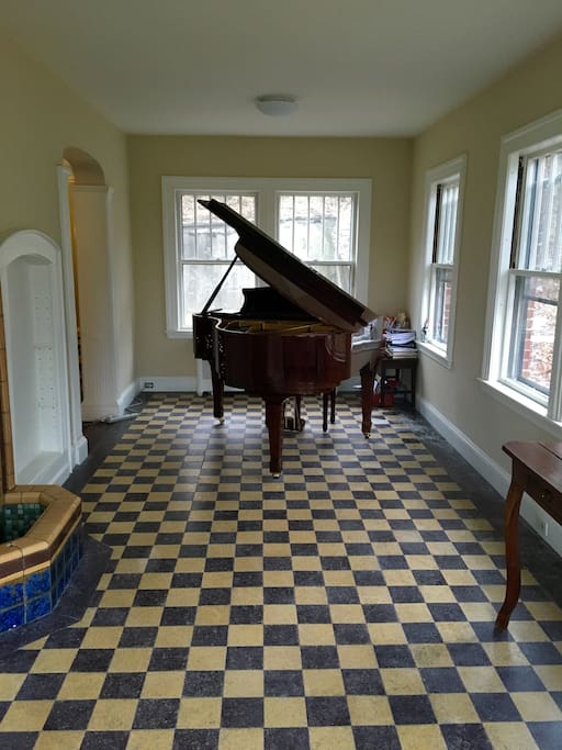 Enclosed sun room with grand piano and violin
