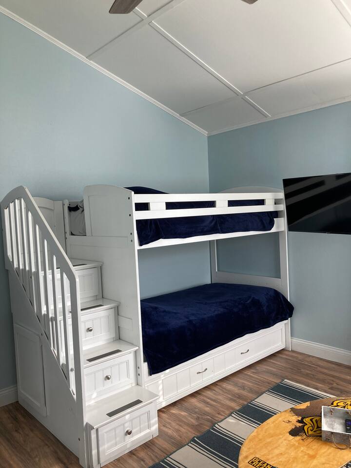 Bunk bed with trundle bed underneath and a smart Roku TV that swivels. Also has blackout curtains. Steps on bunk are drawers also. 