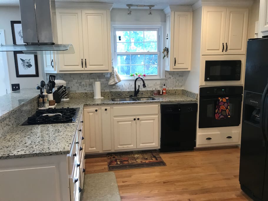 Kitchen with gas stove, granite counter tops, and newly installed backsplash