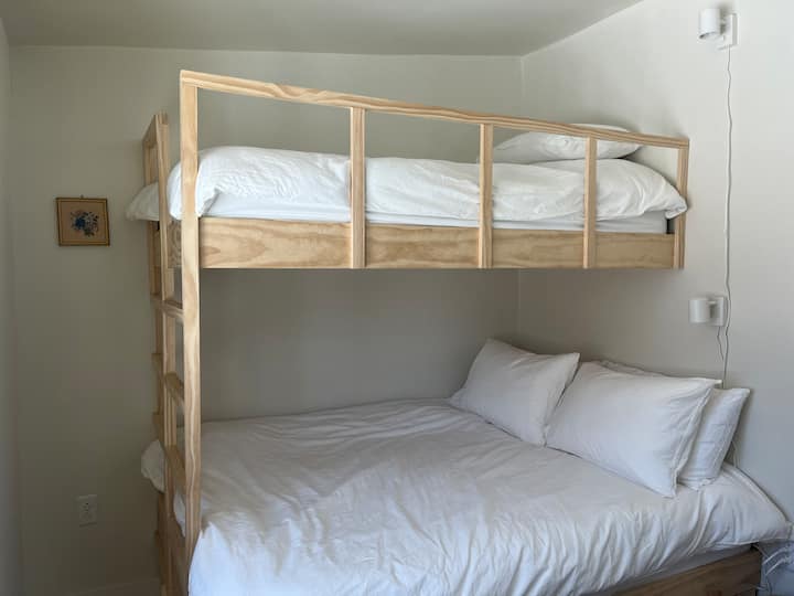 Habitación con literas con cama completa debajo y dos camas individuales arriba