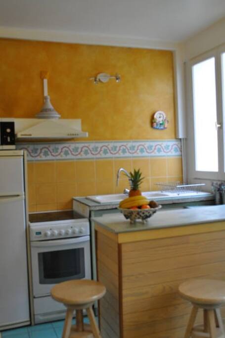 Cuisine, avec cuisinière électrique avec four, micro-ondes, frigidaire-congélateur, plan de travail pour cuisiner, vaisselle à disposition.