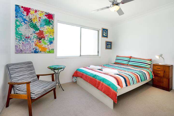 The second bedroom is vibrant and comes with a built-in wardrobe, ceiling fan and extra comfy seating