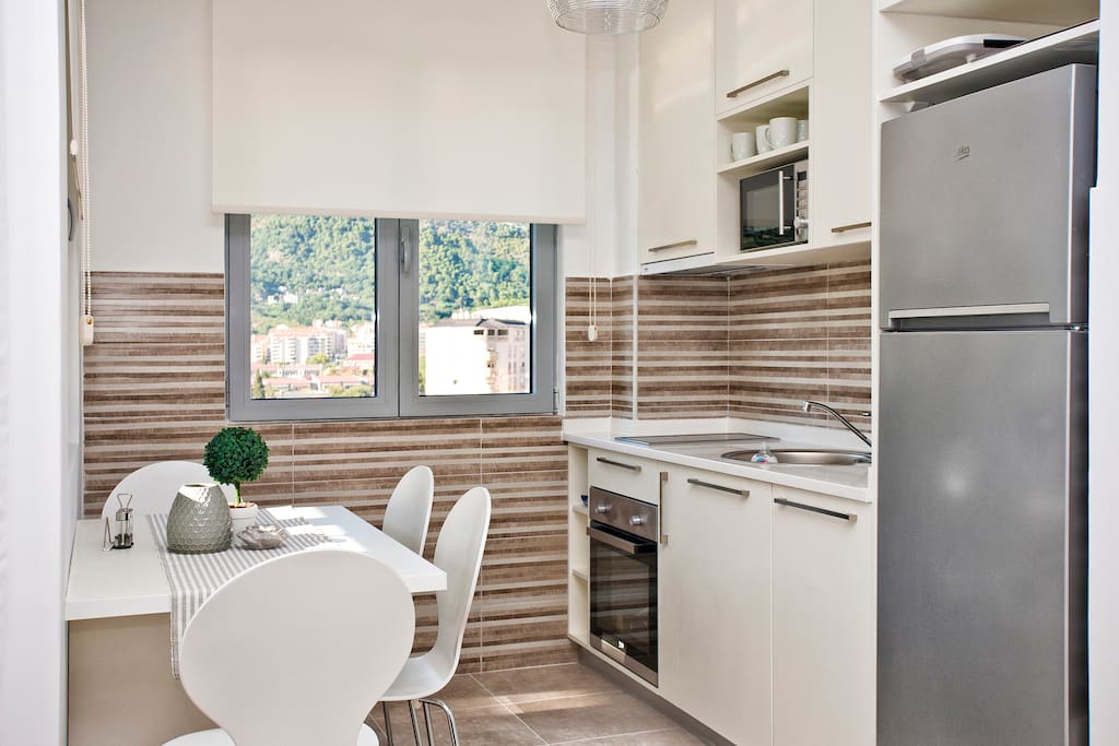 Modern kitchen with many windows and modern appliances. You have microwave, dishwasher, stove, oven and huge fridge.
