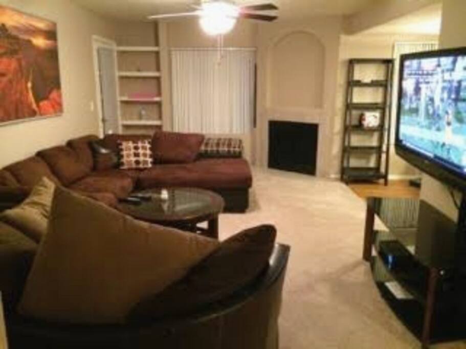 Living Room with large L couch, oversized huge swivel chair, coffee table with additional built-in seating, and 55" TV