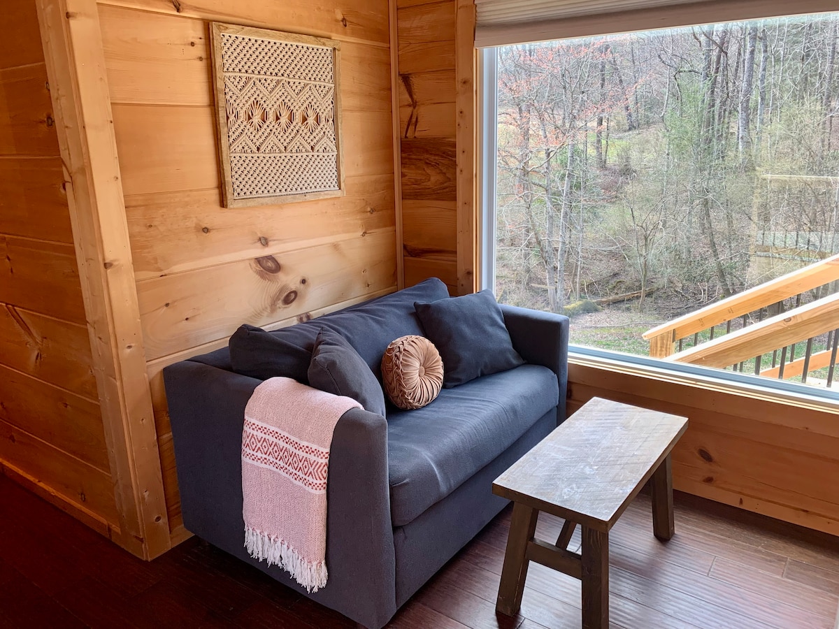 Уживајте во погледот низ големиот прозорец .  Мала рекичка тече низ дворот.