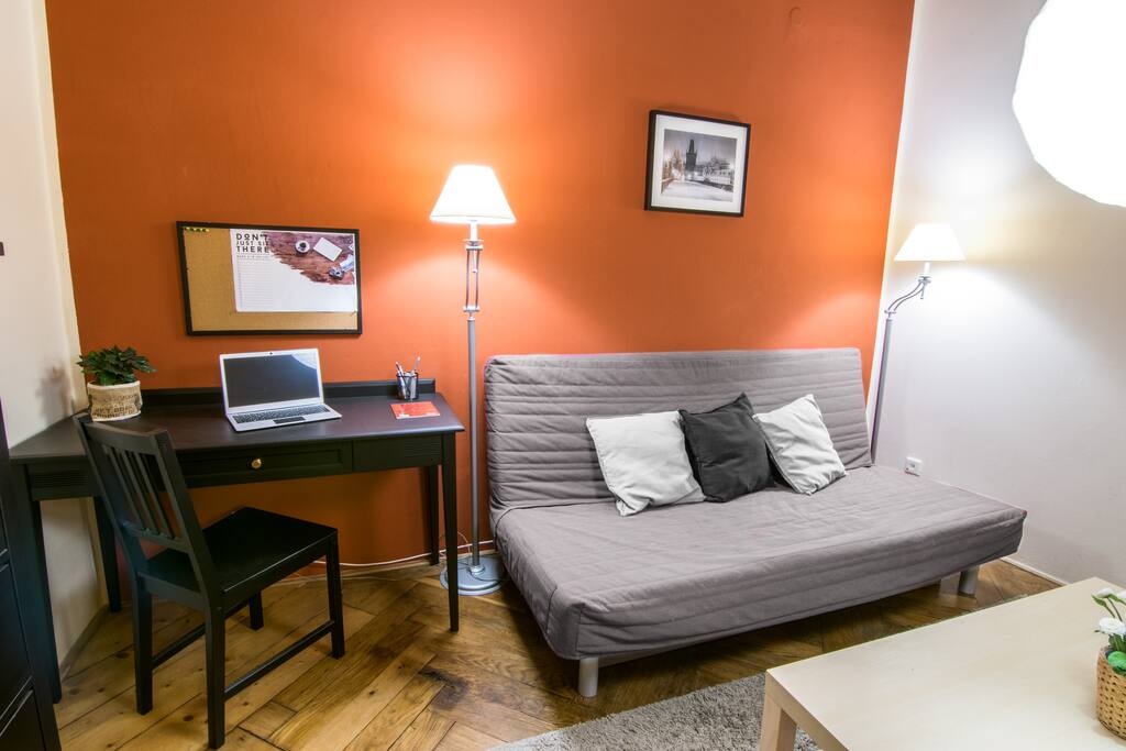 A spacious living room with an original parquet floor. Equipped with folding sofa, two armchairs and television