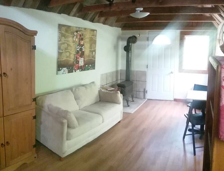 The living space, kitchen and breakfast nook are one open space with abundant light. The couch is also a pull out twin bed for a third person. There is a ladder on a pulley that drops down from the ceiling that leads up to the bedroom. It has a lovely little wood stove and also electric heat.