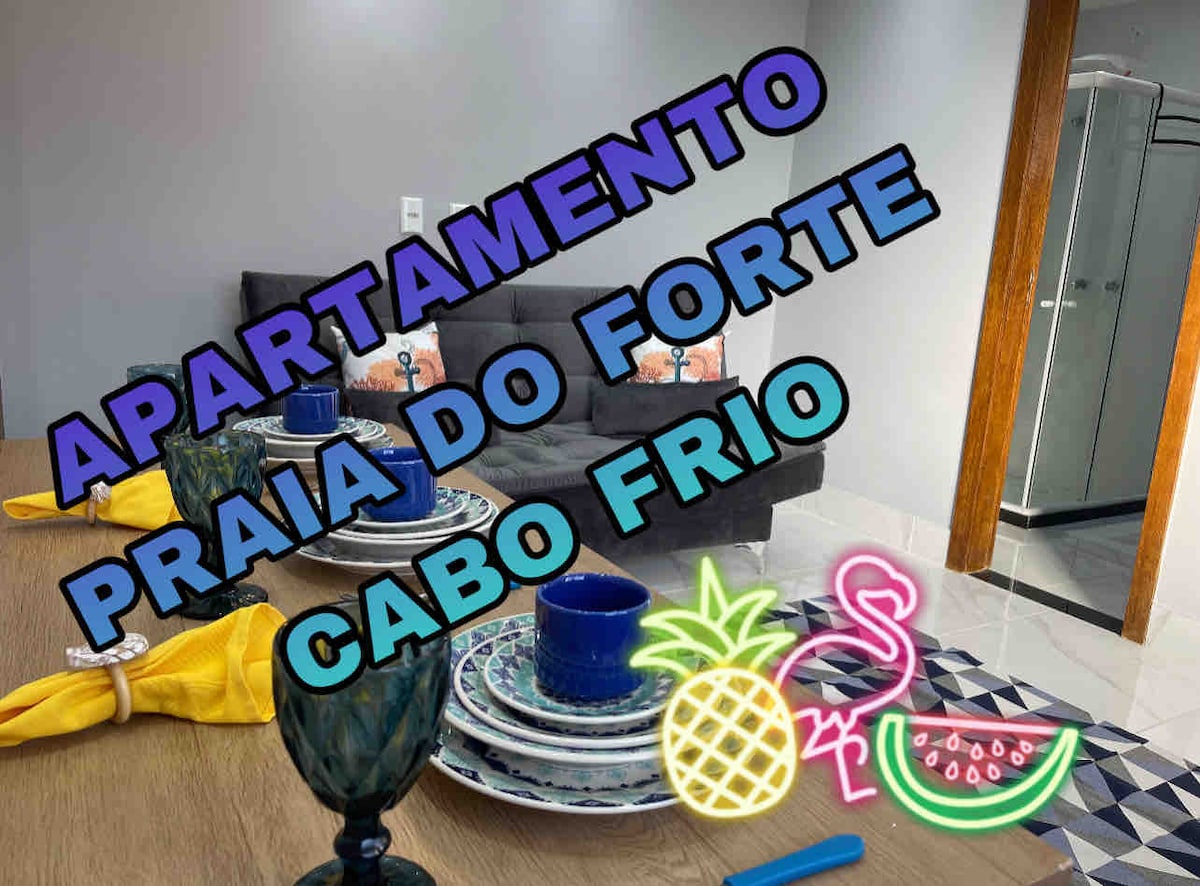 A cozy living area is presented, featuring a dark sofa against the wall and a dining setup with decorative plates, glasses, and blue cups. A modern partition leads to a bathroom in the background, with bright colors adding vibrancy to the space.