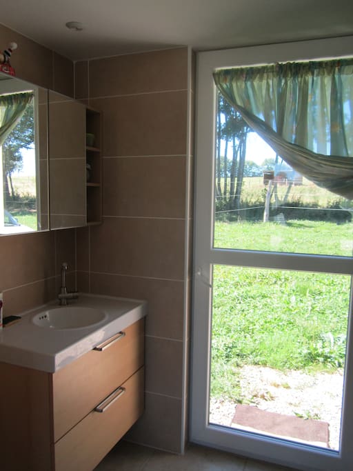 Salle de bain-chambre vue sur le parc chevaux.. porte donnant sur espace vert à disposition transat..