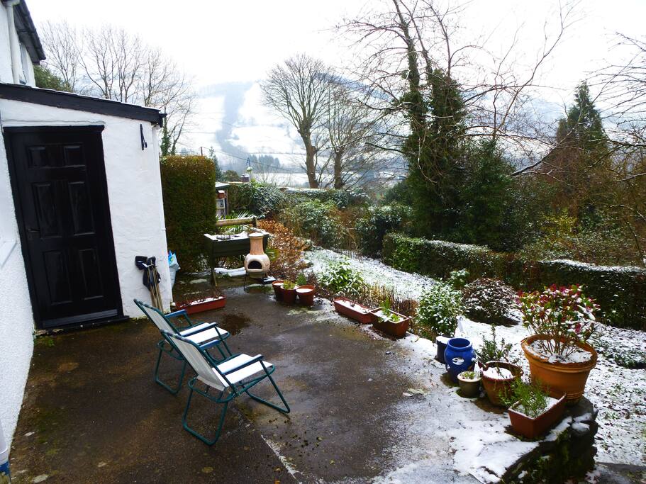 The terrace of the cottage facing the Dyfi Valley after recent snowfall. Good for coffee, birds, meals and the muse!