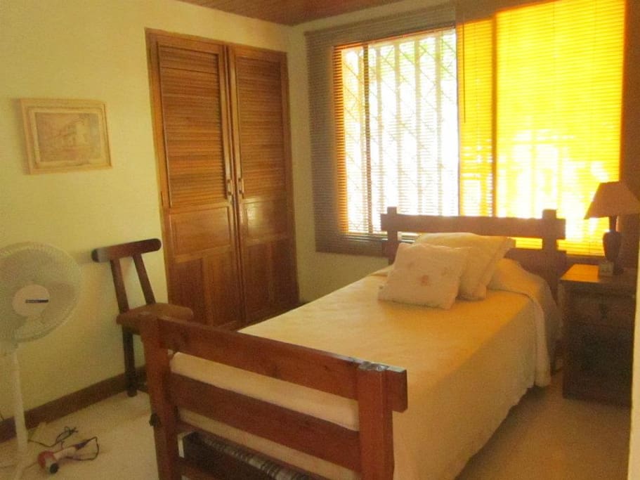 Primer dormitorio con dos camas sencillas, closet, baño privado,television, aire acondicionado y ventilador