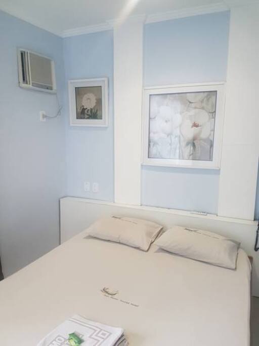 Quarto com ar condicionado, TV e roupa de cama
