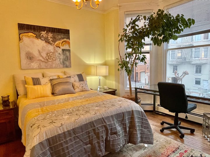 Svetlá slnečná izba, veľká posteľ s originálnym umením a eklektický nábytok