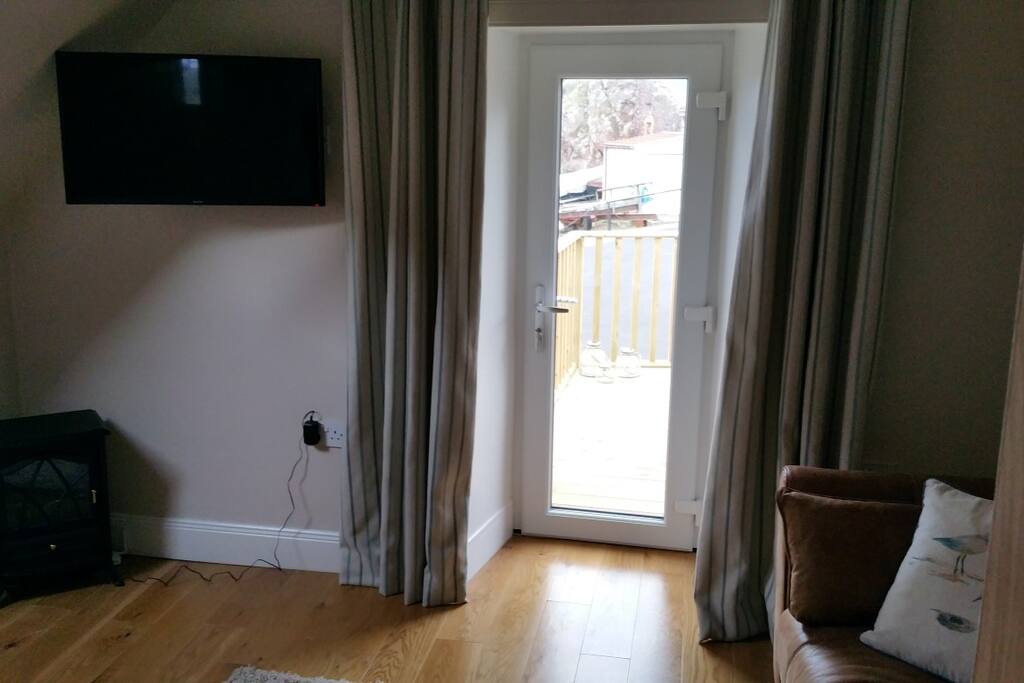 Living room with door out onto decked balcony overlooking the harbour