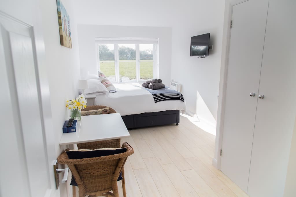 Bedroom with two comfy chairs, table, flat screen tv and fitted wardrobe