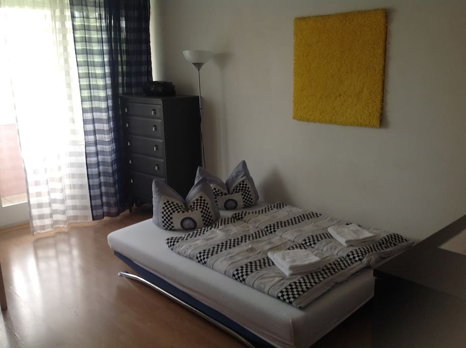 Wohnzimmer mit Schlafcouch und Esstisch