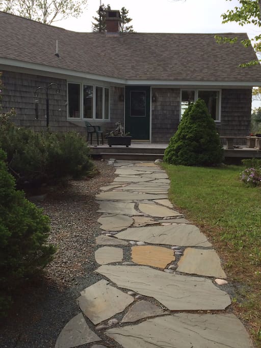 Walkway to the front door, surrounded by gardens on either side.