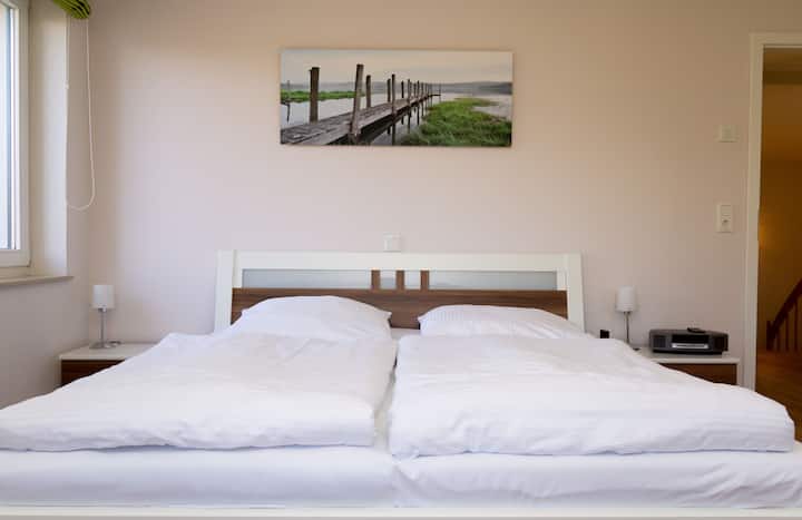 Chambre avec lit double, armoire, console avec chaises et miroir