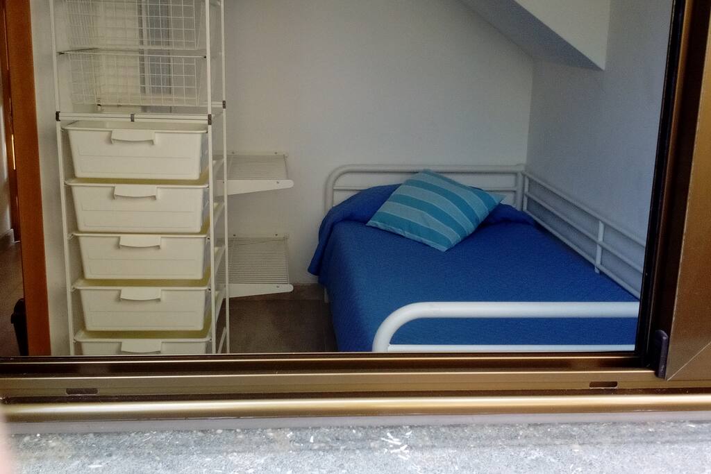 Habitación 2, con 2 camas, una de 70cm, en la otra pueden dormir 2 personas. Guardarropa. Mesa y silla. Con ventana al jardín