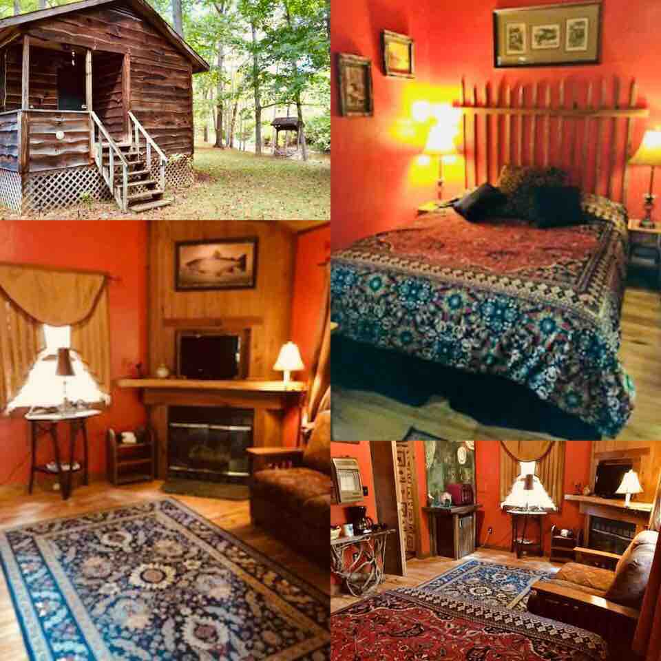 A rustic cabin exterior is framed by trees, showcasing a welcoming entrance with steps. The interior features a queen bed with a patterned duvet, a cozy love seat, and a fireplace. Decorative rugs and artwork add character to the living space, illuminated by soft lighting.