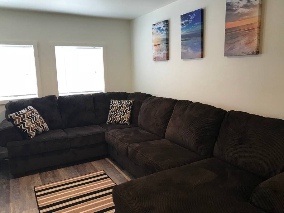 Large cozy sectional couch in main living space with wide-screen Roku TV featuring Roku programming