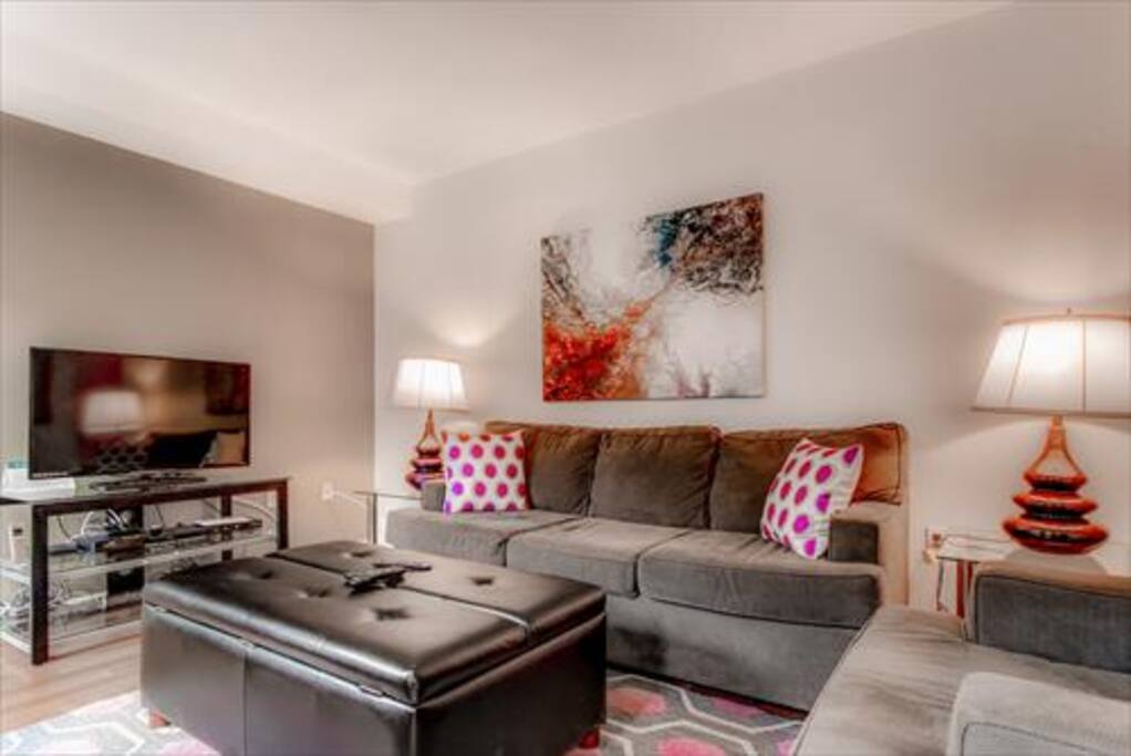 Comfortable living room with pullout sofa bed, club chair and many windows providing lovely natural light