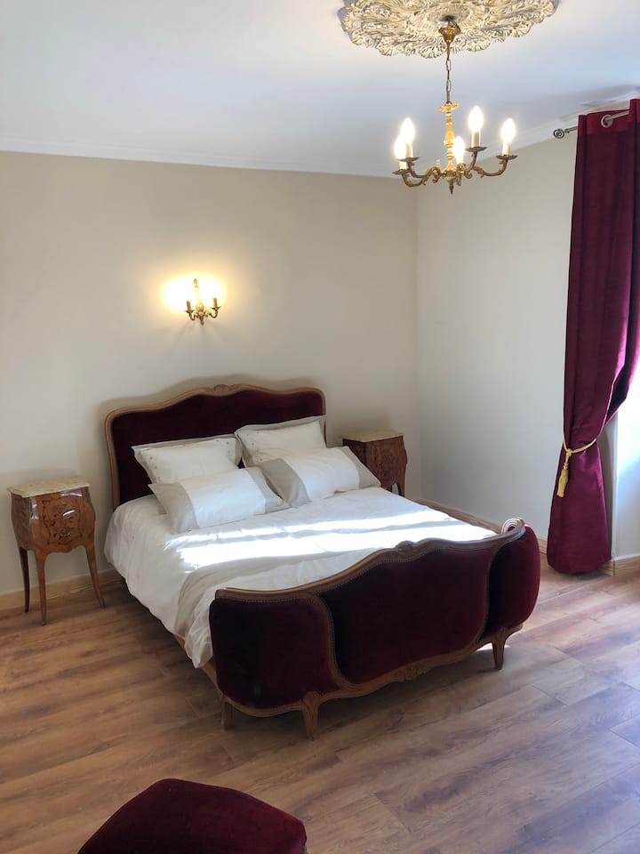 Spálňa na východnej strane s zamatovou posteľou a mramorovými nočnými stolíkmi a ružovým drevom