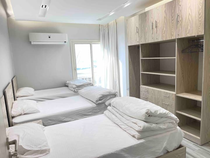 自然光とモダンなデザイン、エレガントな木製家具、そして荷物を快適かつエレガントに収納できる広々としたクローゼットを備えた、家族や友人とのご利用に最適な3つのシングルベッドを備えた快適なベッドルーム